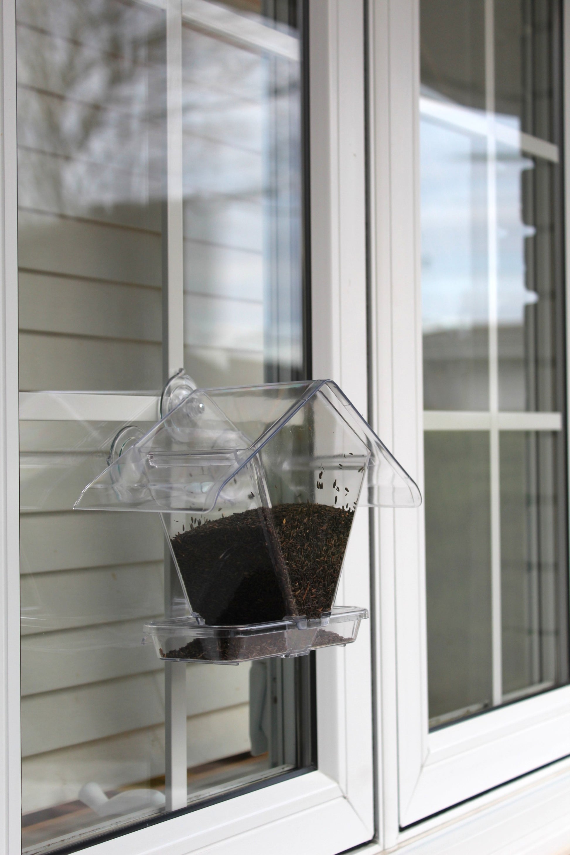 Aspects Window Café clear acrylic bird feeder mounted on exterior window with nyjer seed inside
